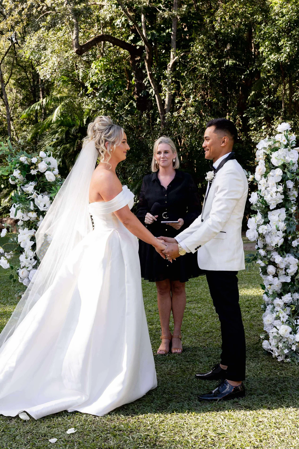 Bec leading a garden ceremony with a couple holding hands