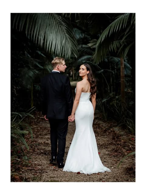 Geneva and Jono holding hands beneath tropical foliage at Sol Gardens.
