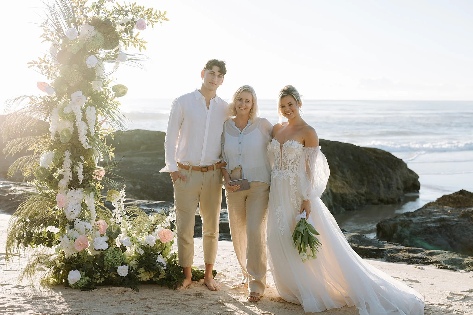 Bec and a newly married couple celebrating by the ocean